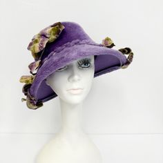 Vintage Lazarus ladies hat, this is a winged cloche or bucket hat, made to be worn low on the brow and tilted. The downturned brim is wider in the front than in the back.   Has ombre velvet trim of leaves and flowers, the stems have been wrapped in the same faux fur the hat is made of.  It is unlined and has a grosgrain sweatband in lavender.  The edge of the brim is rolled under and trimmed in grosgrain ribbon as well. Of a faux or synthetic fur on a wool felt base.   Labeled "Lazarus Model, Paris Cincinnati" and tagged a size 22, it is also stamped "Brigadoon Body Made in Austria".  Measurements are: 22 1/8 inches around the inside of the crown at the sweatband crown is 4 inches deep brim is 4 inches wide at the widest point In good, preworn, vintage condition with no holes, stains, or f Vintage Purple Hat With Short Brim, Vintage Short Brim Purple Hat, Victorian Cloche Hat For Kentucky Derby, Victorian Wide Brim Hat For Kentucky Derby, Purple Wide Brim Hat For Church, Vintage Curved Brim Top Hat For Royal Ascot, Vintage Curved Brim Hats For Races, Victorian Brimmed Hat For Kentucky Derby, Victorian Curved Brim Hat For Church