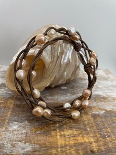 Petite baroque freshwater pearls floating on 3 strands of genuine leather. There are 3 (2mm) barnwood brown leather strands that have been loosely intertwined to create this necklace.  There are a total of 22 freshwater baroque pearls in blush, champagne, and off white colors. The pearls range in size from 7-9mm.  It is not intended that the spacing be the same on these floating pearls. They are randomly placed and secured. The only distressing that has been done is close to the clasp where there are 3 strand barrel knots on either side of the clasp.  The leather may become more distressed as you wear it and this is intended with genuine leather. This necklace would be great for any daytime look, for business, accent a casual dress and even a coastal or country wedding dress.  This necklac Adjustable Multi-strand Bohemian Pearl Necklace, Adjustable Bohemian Multi-strand Pearl Necklace, Brown Hand Wrapped Multi-strand Jewelry, Country Wedding Dress, Peacock Pearl, Baroque Pearl Necklace, Boho Leather, Pearl Earrings Dangle, White Colors