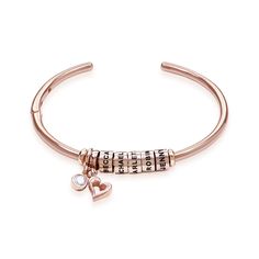 Our Linda Bangle Bracelet in Rose Gold Plating with 0.10 ct Diamond has it all: Up-to-the-minute style, gorgeous personalization, and lots of luxe visual details that make it an eye-catching favorite! Start by adding up to ten personalized beads with one name or word apiece. Our artisans will take care of the finer points, adding a lovely leaf charm and an 0.10ct Lab-grown Diamond for just a touch of classy sparkle! This bracelet is made with 18k Rose Gold Plated Brass and the Beads are 18k ... Elegant Personalized Rose Gold Beaded Bracelet, Rose Gold Jubilee Bracelet As Personalized Gift, Elegant Personalized Rose Gold Beaded Bracelets, Mother's Day Rose Gold Round Bracelet, Personalized Rose Gold Jubilee Bracelet, Personalized Rose Gold Heart Bracelet For Mother's Day, Rose Gold Bracelet With Diamond Accents, Perfect For Gifts, Personalized Rose Gold Bracelet, 14k Gold Filled, Heart-shaped Rose Gold Bracelets With Adjustable Chain