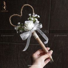 a person holding a white rose and heart shaped boutonniere