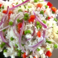 rice with peas, carrots and red onions on a white plate topped with green onions