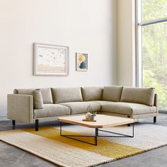 a living room with a sectional couch and coffee table in front of a large window