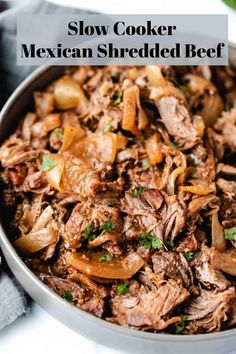 slow cooker mexican shredded beef in a bowl with onions and cilantro on the side