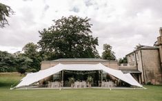 a large white tent set up on top of a lush green field next to a tall building