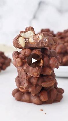 a stack of chocolate covered cookies sitting on top of a white plate next to a bowl of nuts