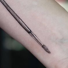 a black and white photo of a pen tattoo on the left arm, it looks like an ink drawing