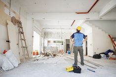 a man standing in an unfinished room with tools