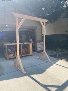 a wooden structure sitting in the middle of a driveway next to a garage with tools on it