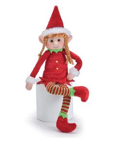 a red and green elf doll sitting on top of a white box with striped stockings