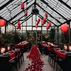 a long table with red rose petals on the floor and lanterns hanging from the ceiling