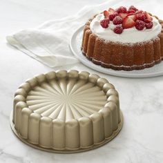 two cakes sitting on top of a table next to each other, one is covered in icing and the other has strawberries