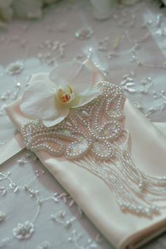 a close up of a white cloth with flowers on it and pearls around the edges