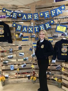 a woman standing in front of a display of shirts and other items on wooden pallets