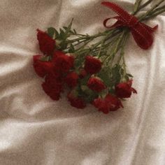 some red roses are laying on a white sheet