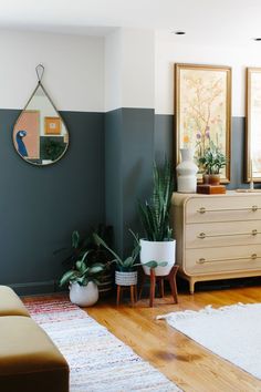 a living room with two plants and a mirror on the wall