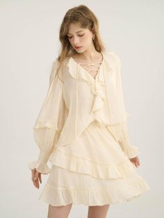 This product brings a touch of vintage-inspired charm, showcasing ruffled details that impart a romantic, nostalgic feel. The blouse stands out with its cascading ruffles around the neckline and down the front, paired with a lace-up detail that offers a subtle hint of allure. Its puffed sleeves with gathered cuffs add a voluminous, soft structure, encapsulating a blend of classic style and modern femininity. - This blouse features an intricate ruffle design that frames the face and adds a dimensional aesthetic to the garment- The lace-up front detail provides a customizable fit and lends a bohemian elegance to the blouse- Its puffed sleeves with elasticized cuffs create a blouson effect that’s both flattering and on-trend- A subtle, handcrafted medal decoration on the lower righ Chic Ruffled Blouse For Spring, Feminine Ruffled Blouse For Brunch, Feminine Tiered Ruffle Tops, Billowy Ruffled Blouse For Spring, Spring Billowy Blouse With Ruffles, Spring Billowy Ruffle Blouse, Spring Billowy Ruffled Blouse, Feminine Ruffled Blouse For Daywear, Cottagecore Ruffle Blouse For Summer