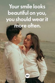 a man and woman standing next to each other on the beach with text that reads, your smile looks beautiful on you, you should wear it more often