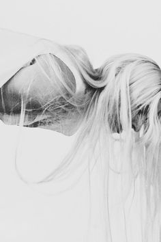 a black and white photo of a woman with her hair blowing in the wind