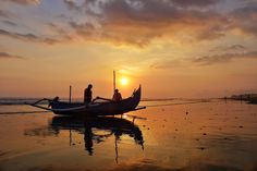 two people in a boat on the beach at sunset