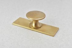 a brass cabinet knob on a white surface