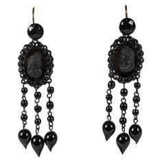 Victorian long french jet earrings of faceted and smooth jet cabocheons, round beads and tear drop shaped drops. With focal cameo ovals facing one another. Blackened steel fittings. Excellent Condition, French wire ear hooks. Length 2.75" x Width .75" Victorian Collar, Purse Boutique, Victorian Bracelet, Gold Pocket Watch, Victorian Engagement Rings, Rhinestone Choker Necklace, Cameo Earrings, Rhinestone Choker, Victorian Gold