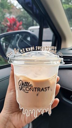 a person holding up a cup of coffee in their hand with the words little contrast written on it