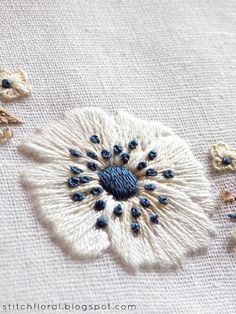 an embroidered flower with blue and white beads on it's center, surrounded by other flowers