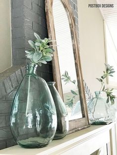 two vases with flowers sit on a mantle in front of a mirror and fireplace mantel