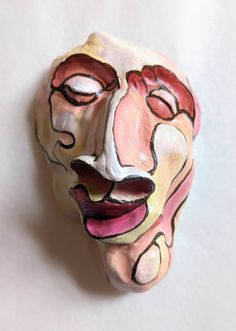 a ceramic face is shown on a white surface