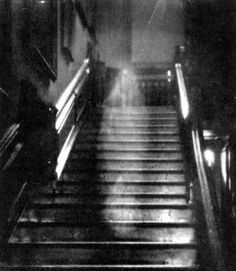 black and white photograph of an escalator with light coming from the top down