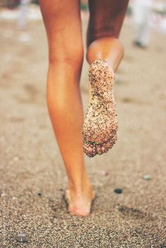 a person walking on the beach with sand in their feet