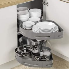 a kitchen cabinet with plates and pans in the pull out drawer that is open