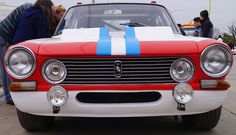 an old red and white car with blue stripes on it's front grills