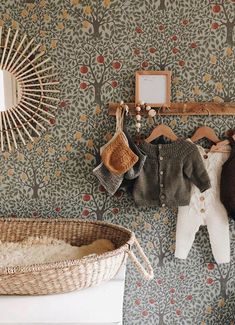 there is a baby's clothes hanging up on the wall next to a basket