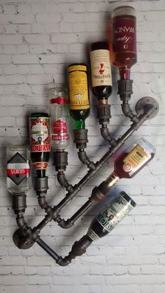 a wine rack made out of pipes and liquor bottles is shown in front of a white brick wall