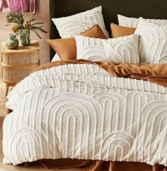 a bed with white and brown comforters in a room next to a night stand