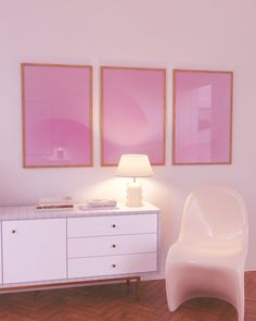 a white chair sitting next to a lamp on top of a wooden floor in front of two pink paintings