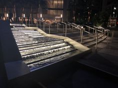 the water is running down the steps in the city at night, with lights shining on them