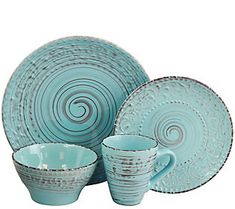 a set of blue dishes and cups with swirl designs on the rims, in front of a white background