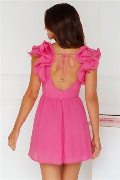 a woman wearing a pink dress with ruffles on the back