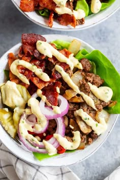 two white bowls filled with salad and dressing on top of a blue table cloth next to each other