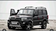 a black suv parked on top of a sandy beach