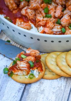 some crackers are sitting on a table next to a bowl of shrimp and sauce