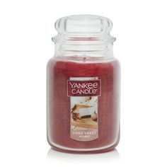 yankee candle in a glass jar with red wax and white frosting on the lid