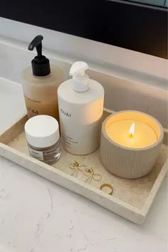 a bathroom sink with soap, lotion and candles