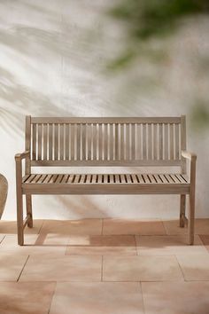 a wooden bench sitting on top of a tiled floor next to a potted plant