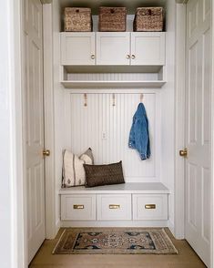 an entryway with white cabinets and drawers