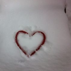 a heart drawn in the snow by someone's hand