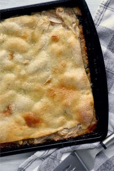 a casserole dish with meat and cheese in it sitting on a table next to a fork