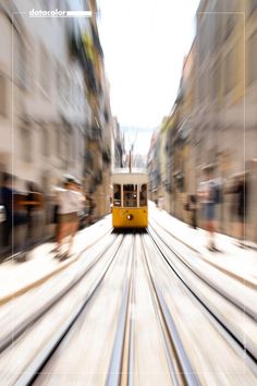 a yellow tram traveling down a street next to tall buildings